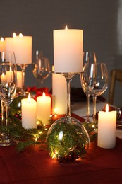 Christmas celebration. Burning candles, glasses and festive decor on table