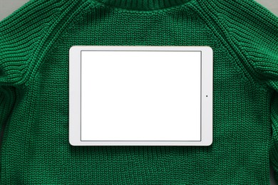 Photo of Modern tablet on green sweater, top view. Space for text