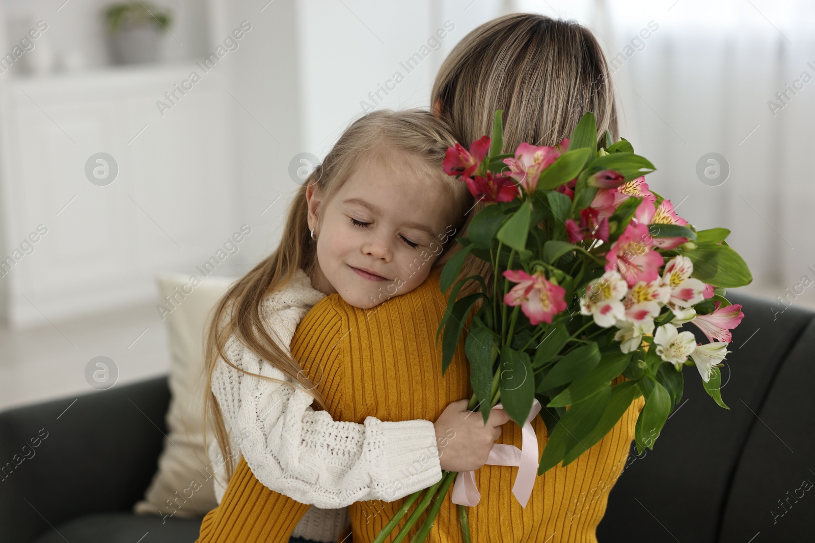 Photo of Little daughter congratulating her mom with bouquet of alstroemeria flowers at home. Happy Mother's Day