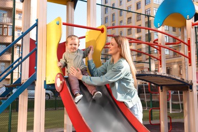Photo of Happy nanny and cute little boy on slide at playground