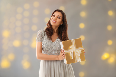 Image of Beautiful woman with Christmas gift on blurred background