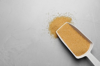 Photo of Brown sugar and scoop on light grey table, flat lay. Space for text