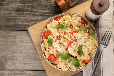 Photo of Delicious pasta with tomatoes, basil and parmesan cheese served on wooden table, flat lay. Space for text