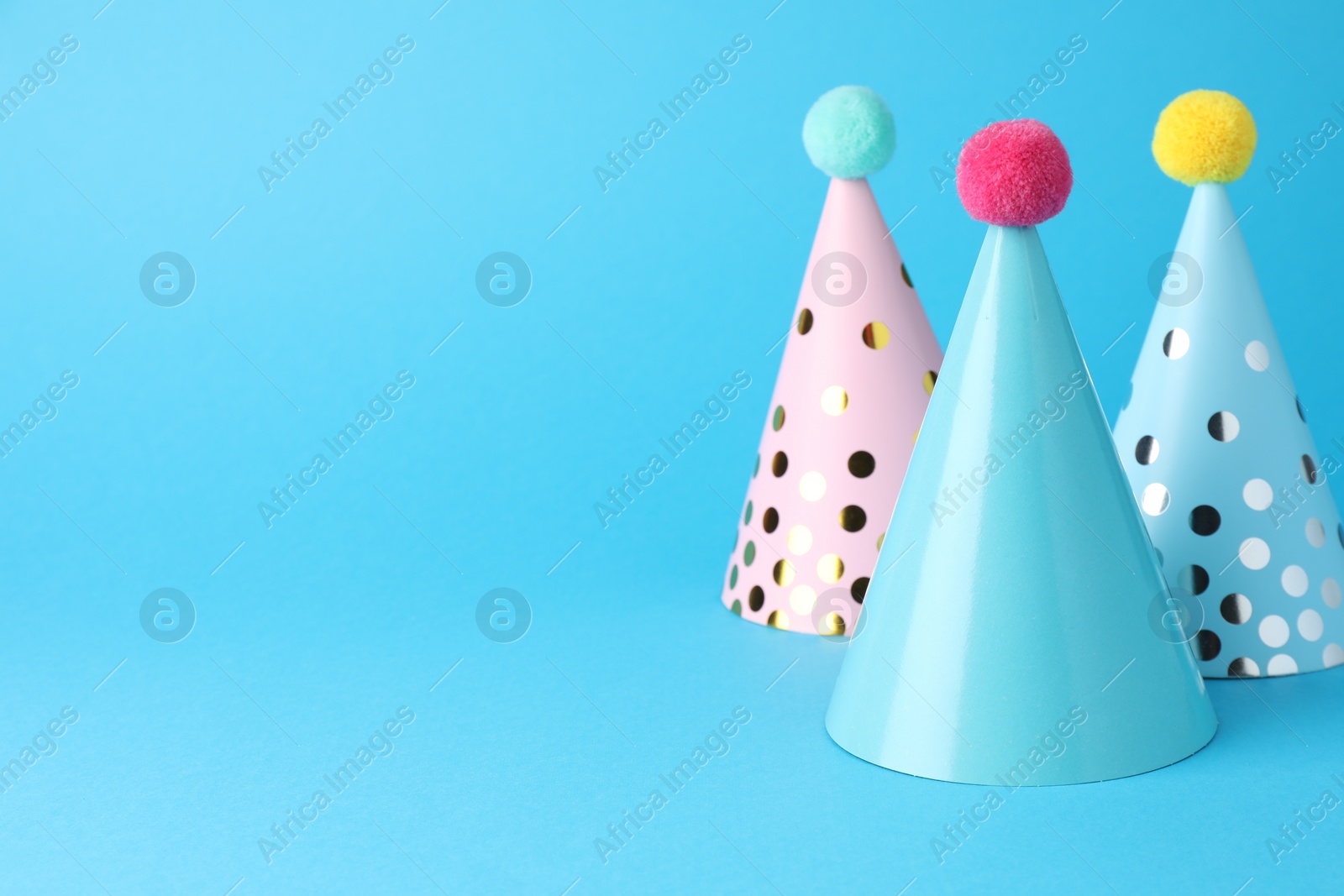 Photo of Colorful party hats on light blue background, space for text