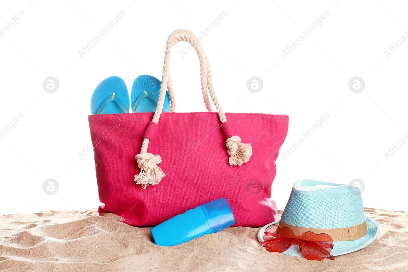 Photo of Stylish coral bag and beach accessories on sand against white background