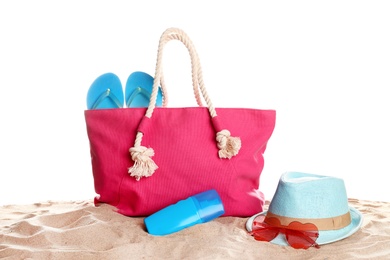 Photo of Stylish coral bag and beach accessories on sand against white background