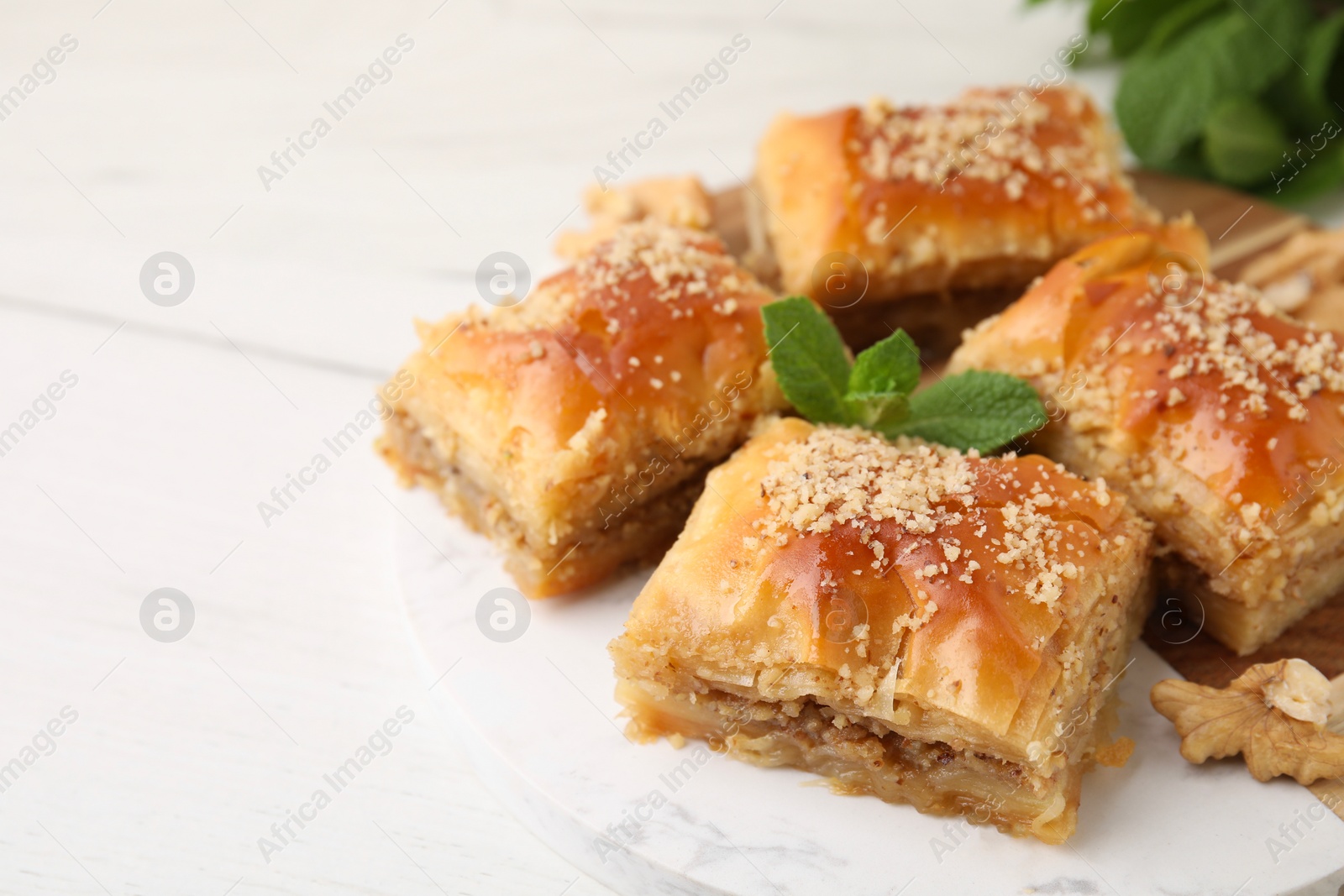 Photo of Eastern sweets. Pieces of tasty baklava on white wooden table, closeup. Space for text