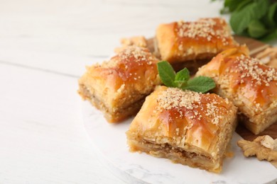 Photo of Eastern sweets. Pieces of tasty baklava on white wooden table, closeup. Space for text