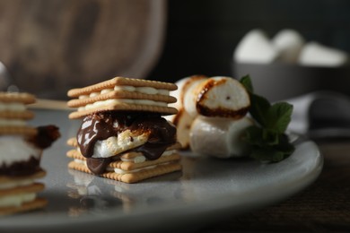 Delicious marshmallow sandwiches with crackers and chocolate on grey plate, closeup