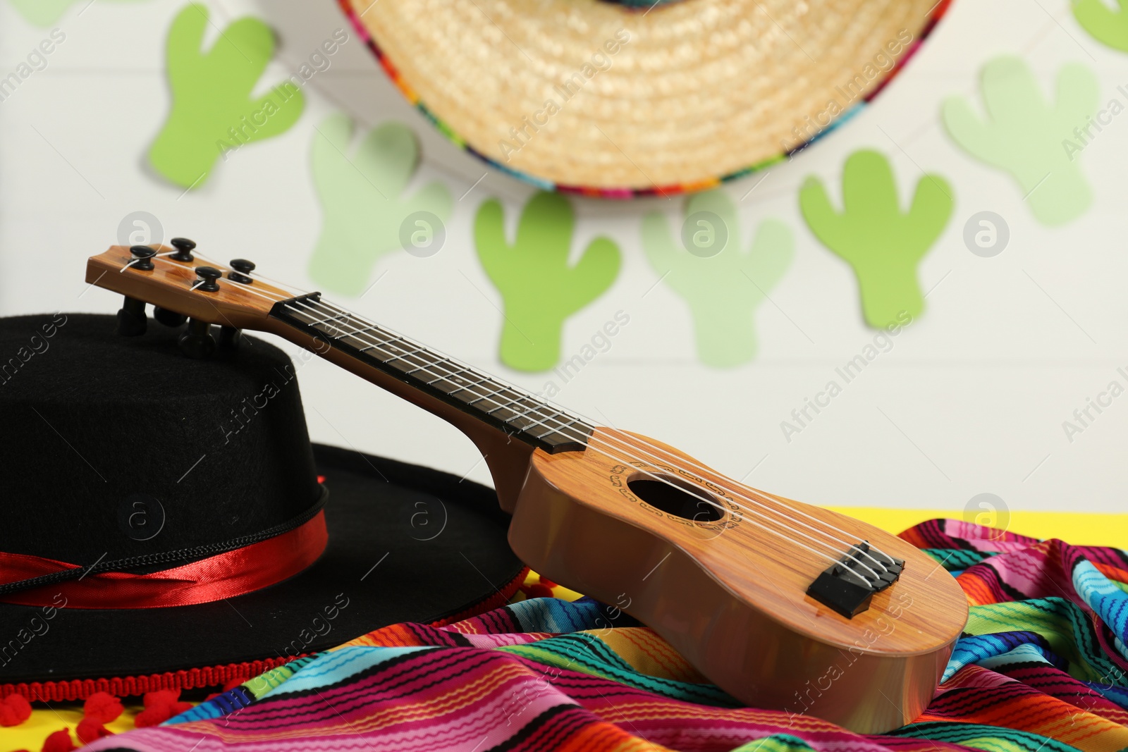 Photo of Black Flamenco hat, poncho and ukulele on table, closeup
