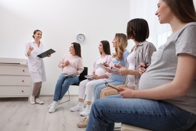Photo of Group of pregnant women with doctor at courses for expectant mothers indoors
