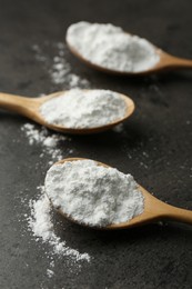 Baking powder in spoons on grey textured table, closeup