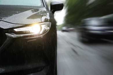 Black car driving at high speed on rainy day outdoors, closeup with motion blur effect. Space for text