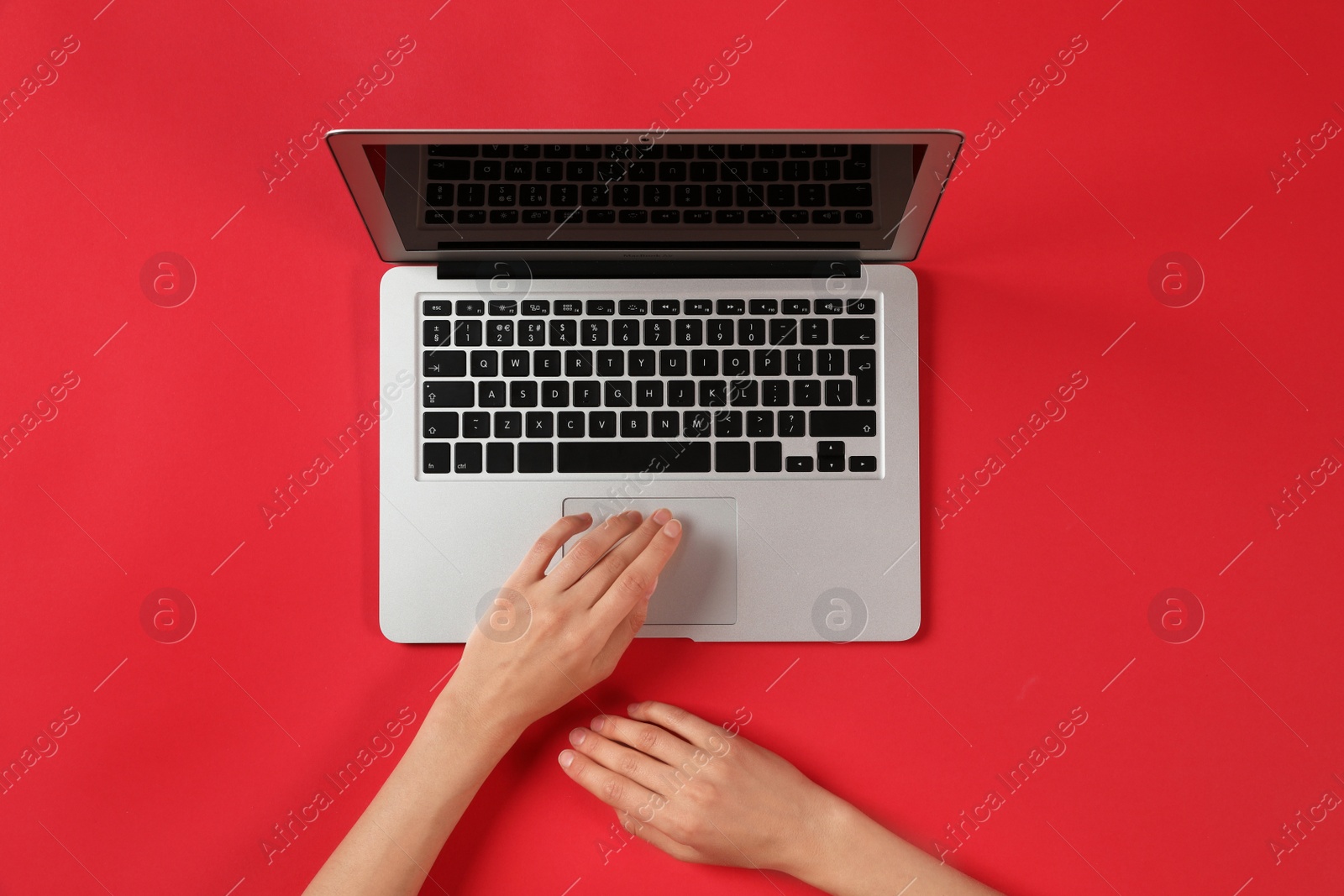 Photo of Woman using modern laptop at color table, top view