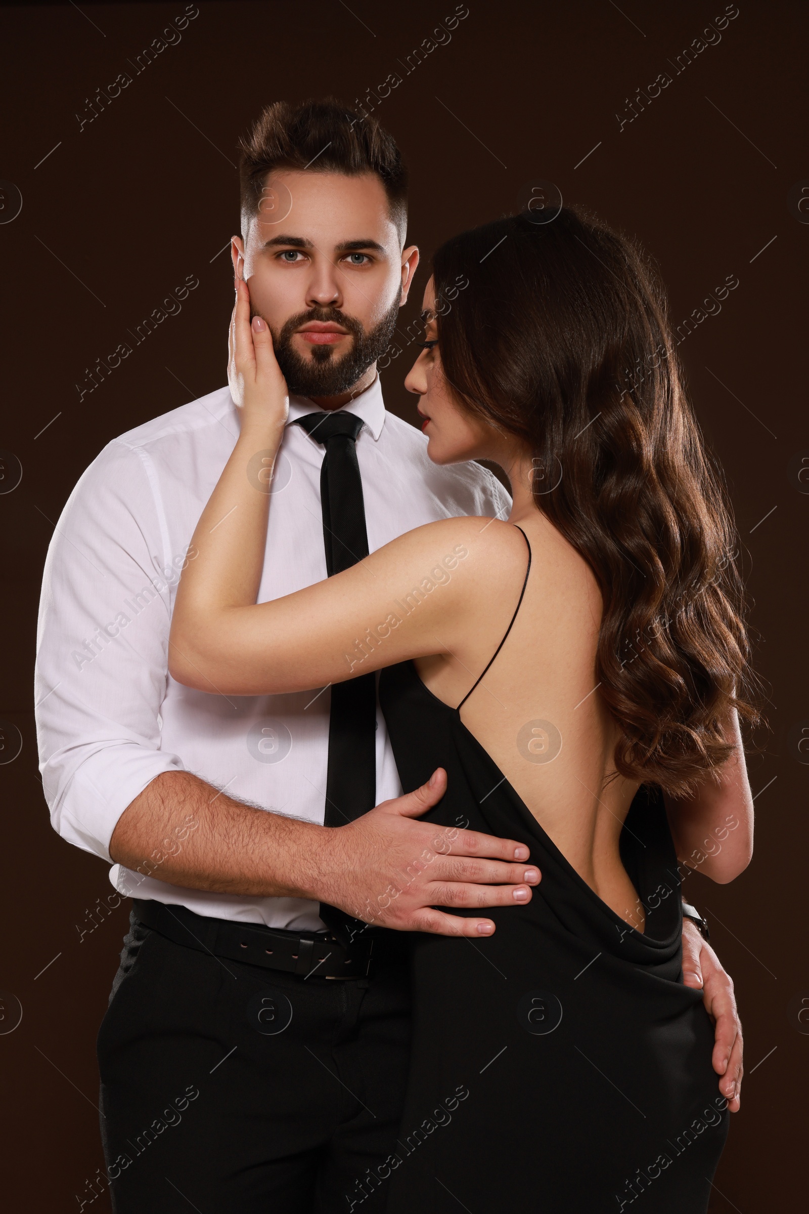 Photo of Handsome bearded man with sexy lady on dark brown background