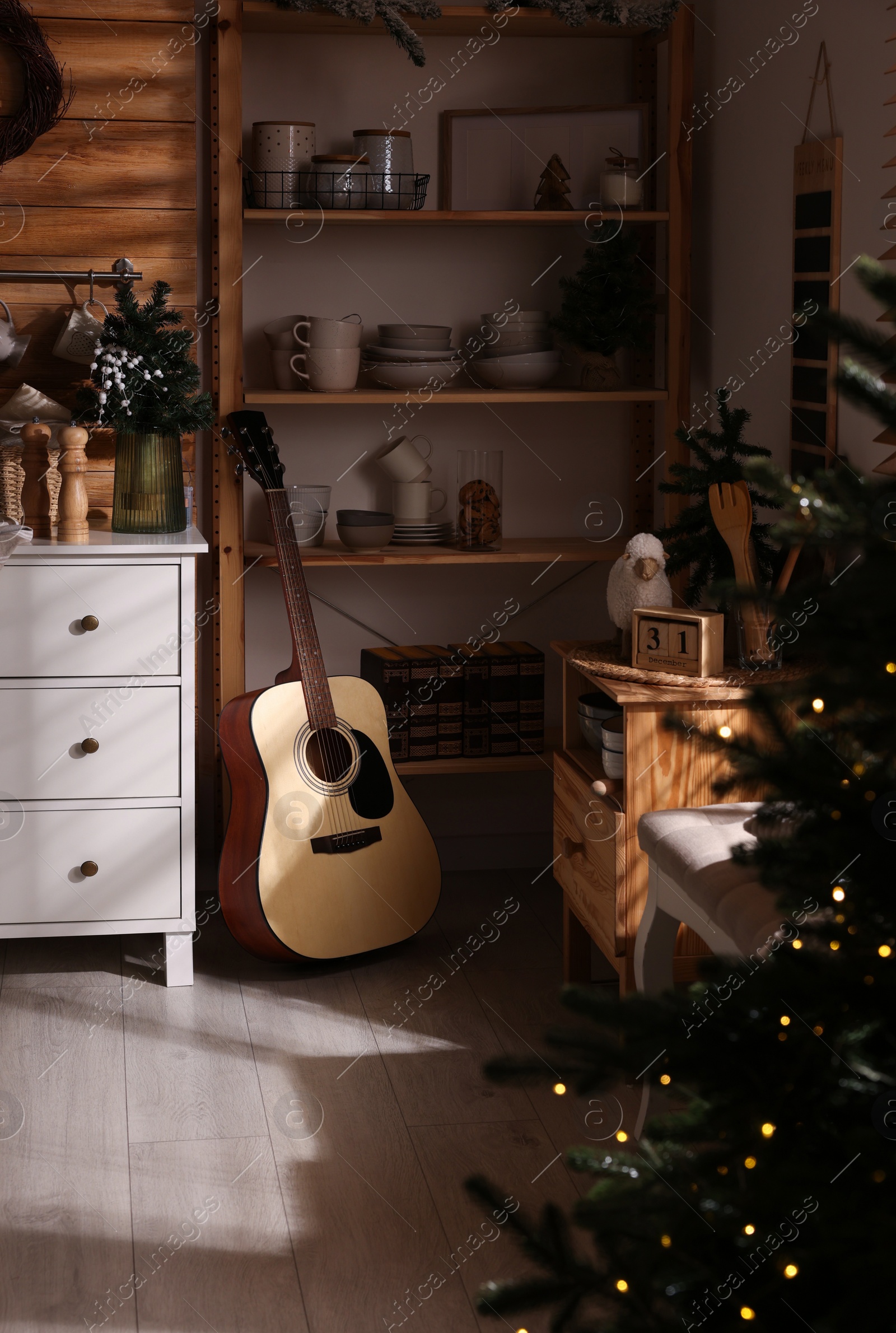 Photo of Stylish kitchen interior with Christmas tree and guitar