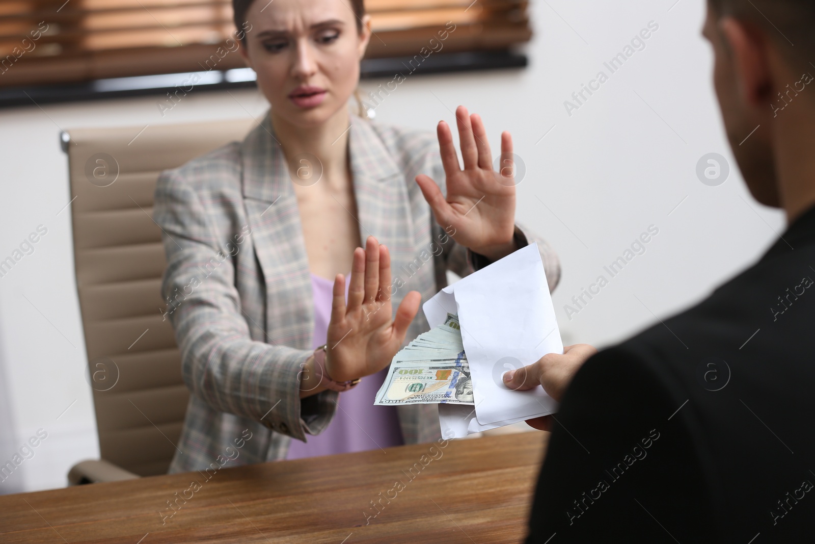 Photo of Woman refusing to take bribe at table indoors