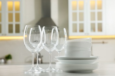 Photo of Different clean dishware and glasses on white marble table in kitchen