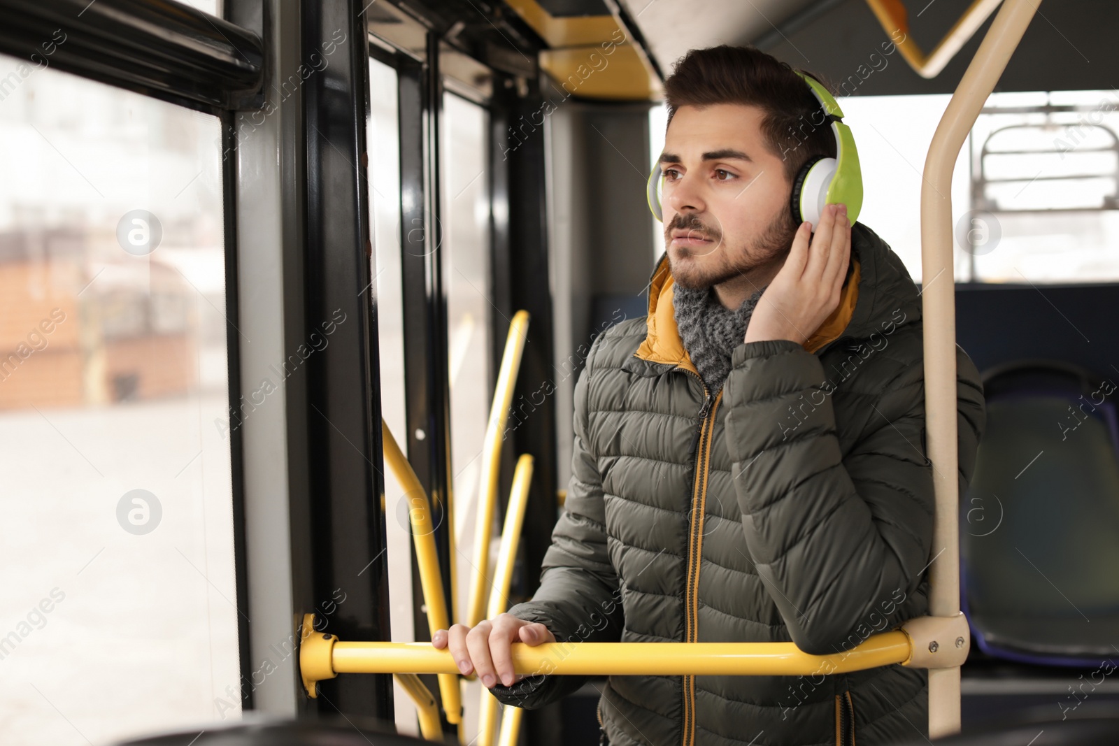 Photo of Young man listening to music with headphones in public transport