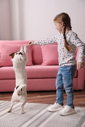 Photo of Cute little girl playing with her dog at home. Childhood pet