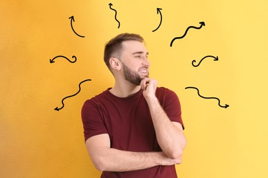 Image of Choice in profession or other areas of life, concept. Making decision, young man surrounded by drawn arrows on yellow background