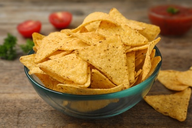 Photo of Bowl of Mexican nacho chips on wooden table, closeup