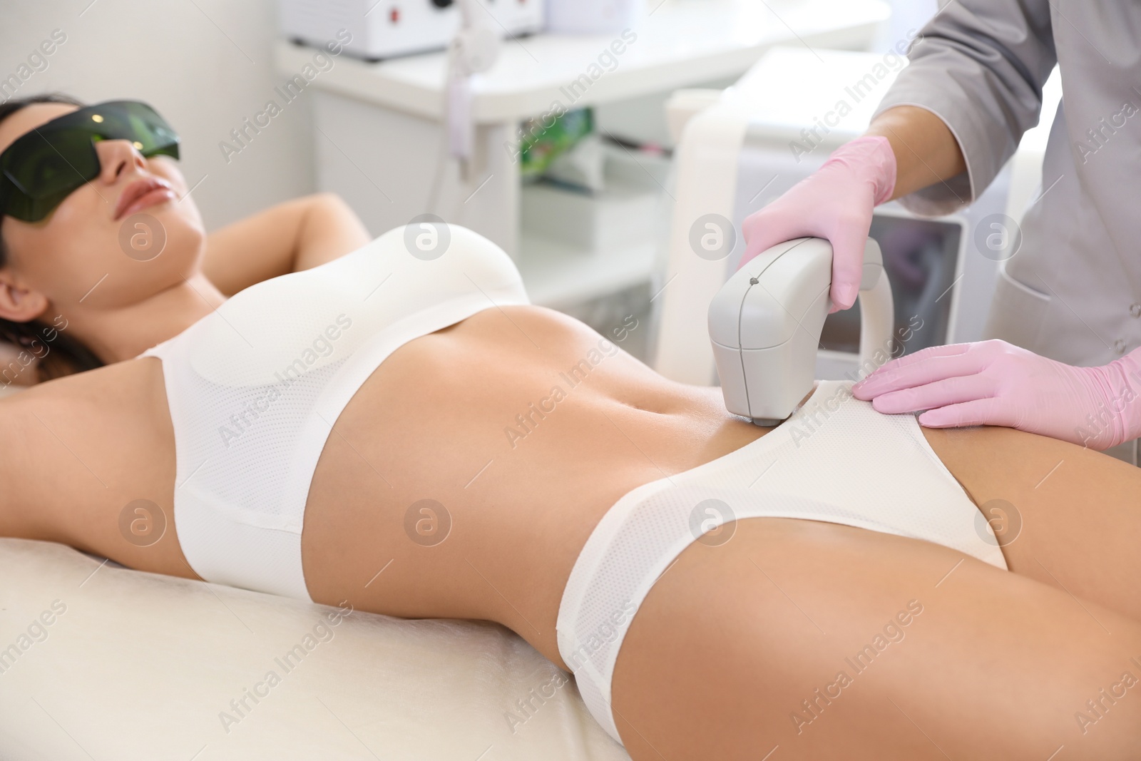 Photo of Young woman undergoing laser epilation procedure in beauty salon