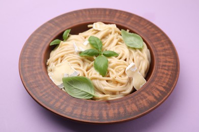 Delicious pasta with brie cheese and basil leaves on violet table, closeup