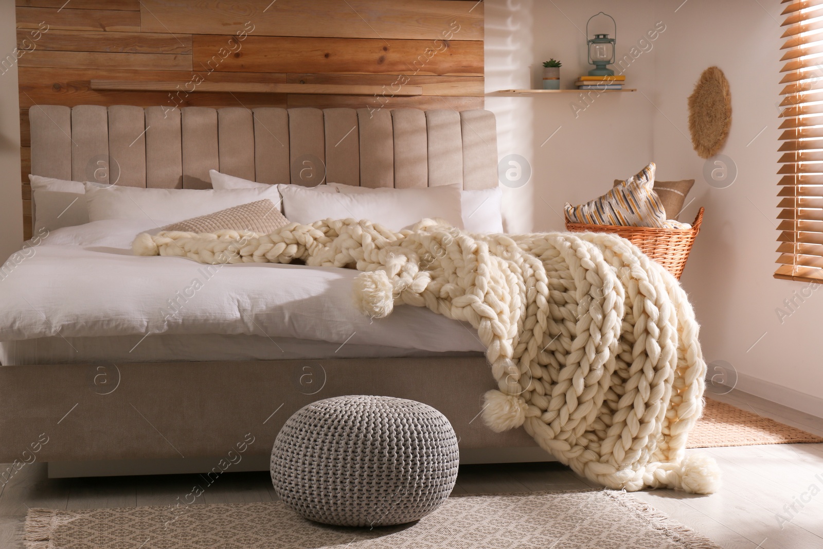 Photo of Bed with white knitted plaid in room. Interior design