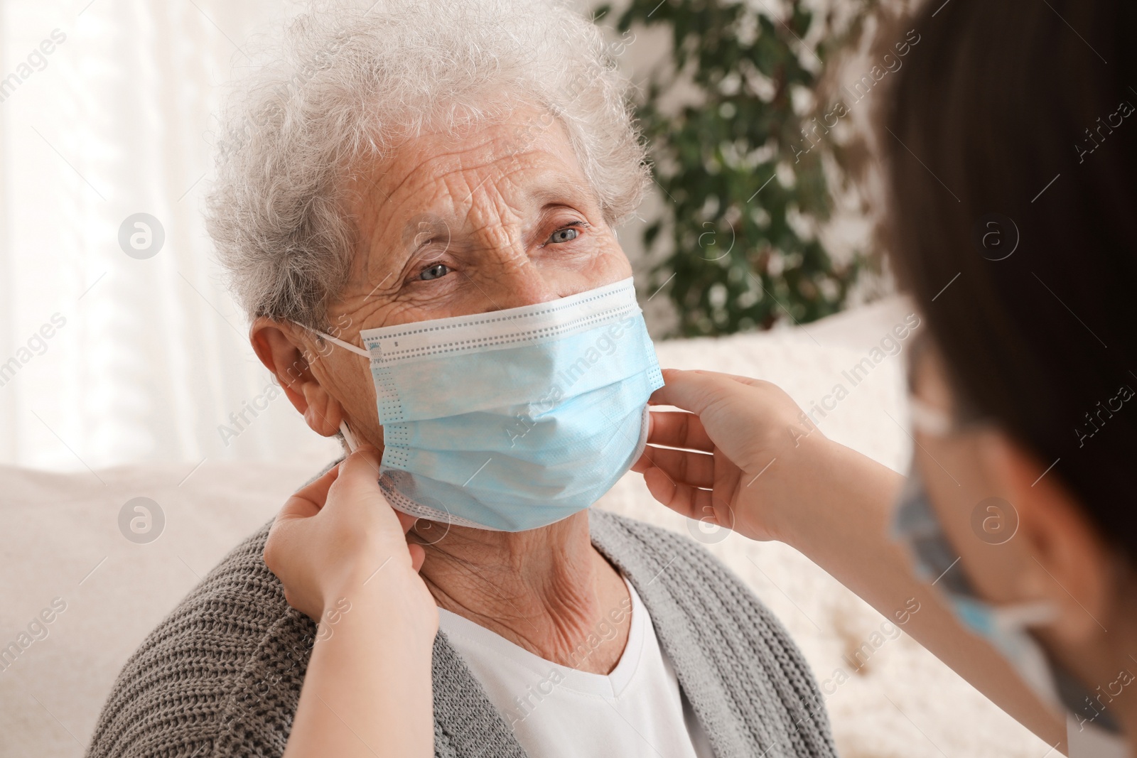 Photo of Doctor putting protective mask on senior woman at nursing home