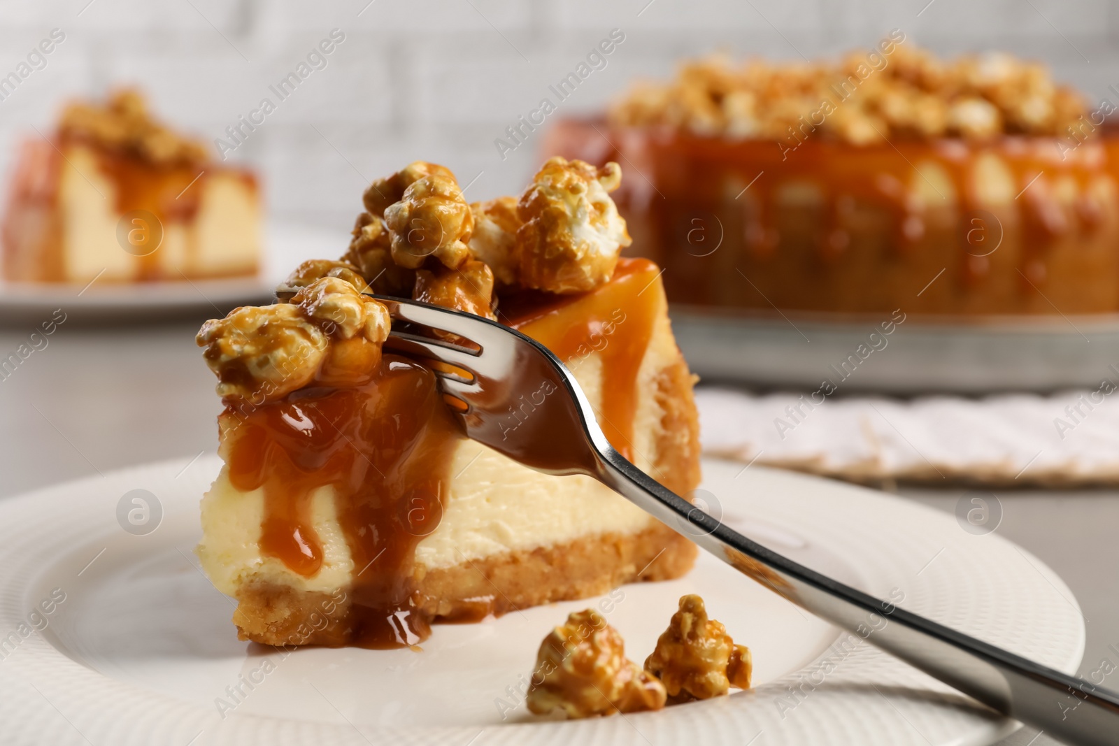 Photo of Piece of delicious caramel cheesecake with popcorn on plate, closeup