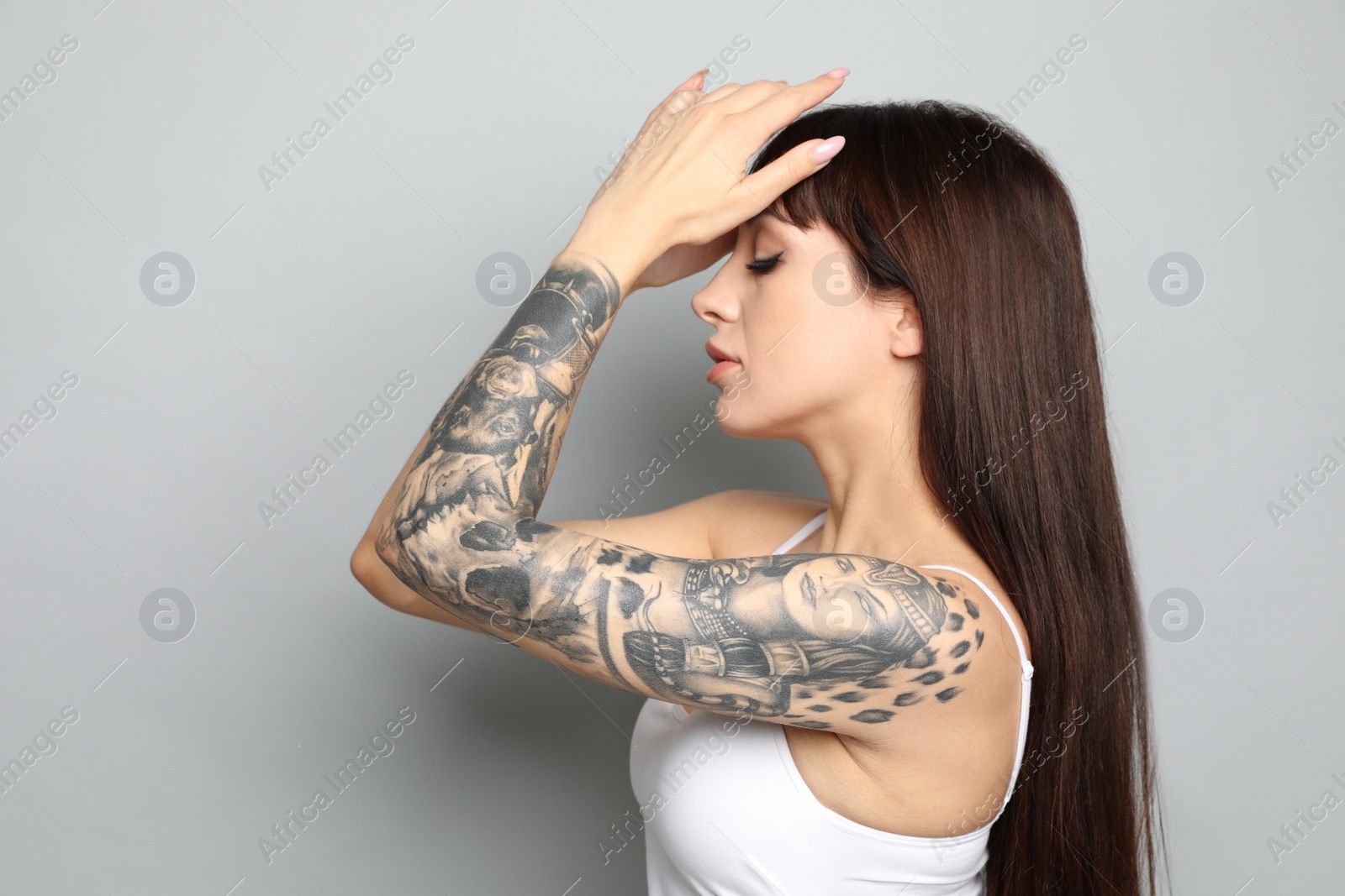 Photo of Beautiful woman with tattoos on arm against grey background