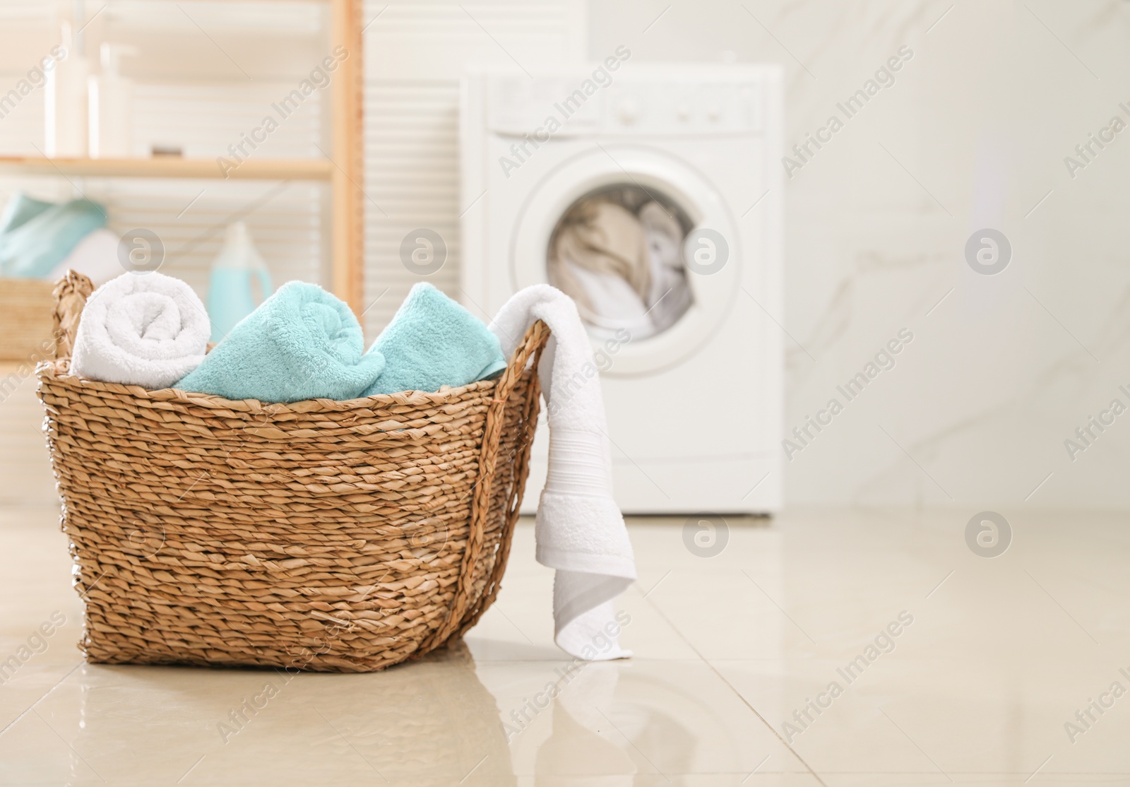 Photo of Wicker basket with fresh rolled towels in bathroom. Space for text