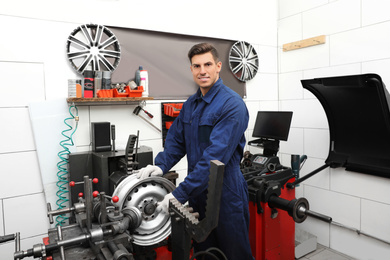 Photo of Man working with car disk lathe machine at tire service