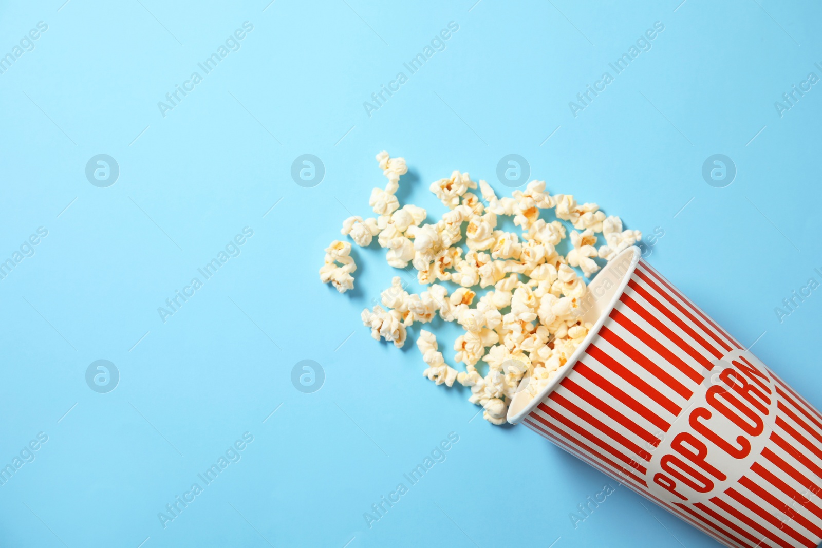 Photo of Cup with fresh tasty popcorn on color background, top view. Cinema snack