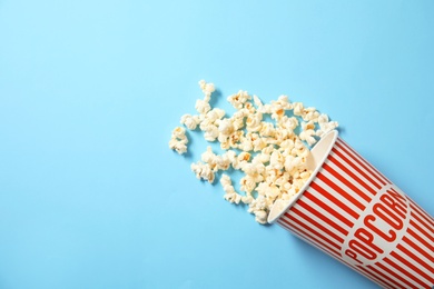 Photo of Cup with fresh tasty popcorn on color background, top view. Cinema snack