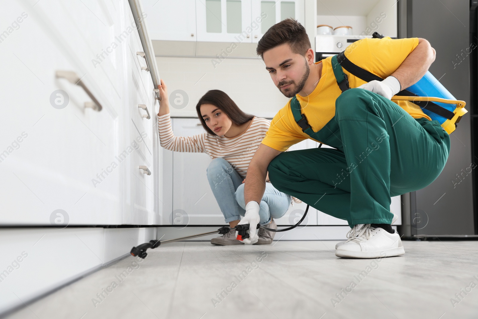 Photo of Woman showing insect traces to pest control worker in kitchen