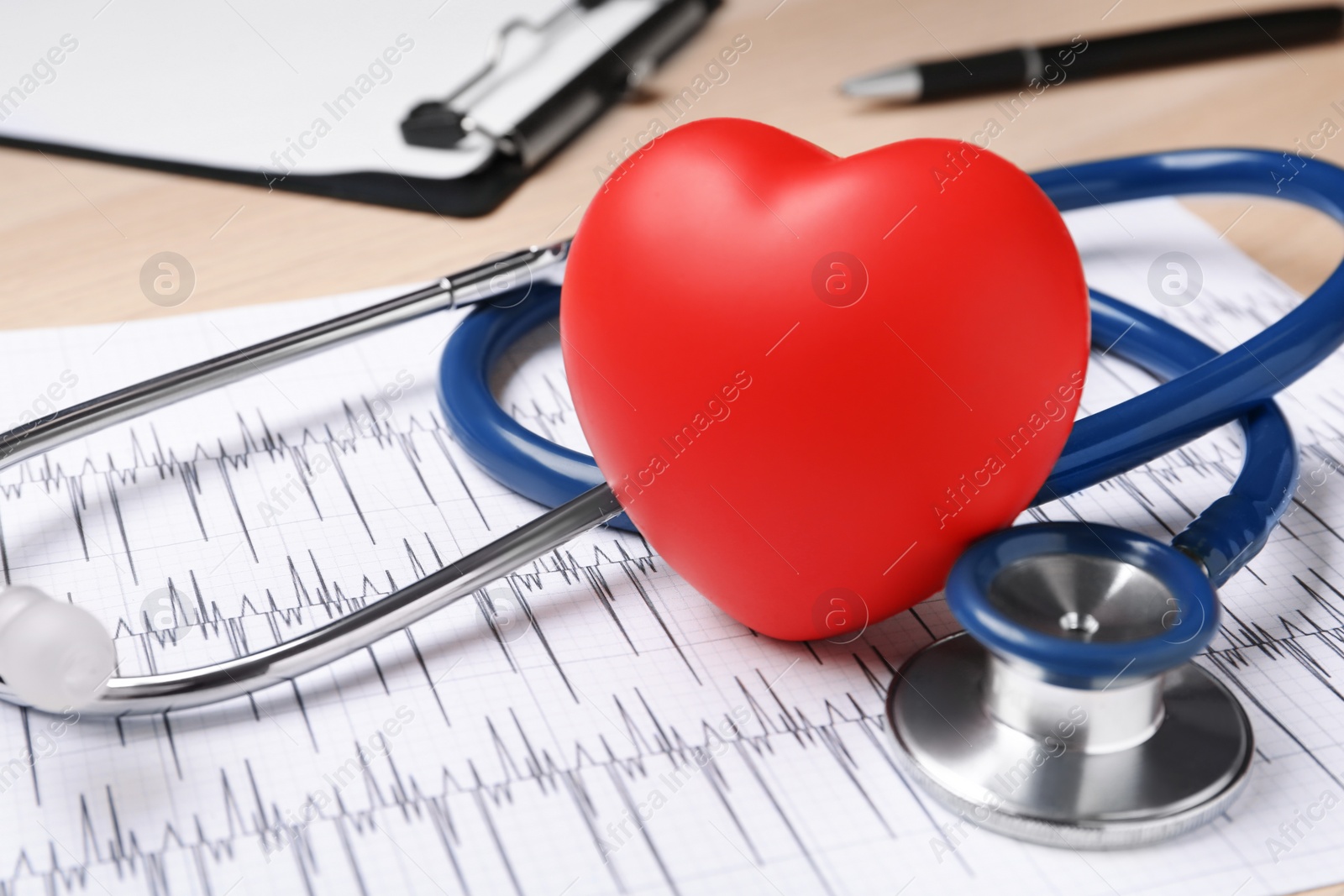 Photo of Stethoscope, cardiogram and red decorative heart on wooden background, closeup. Cardiology concept