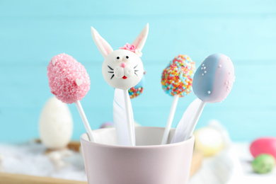 Different delicious sweet cake pops on light blue background, closeup. Easter holiday