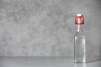 Photo of Glass bottle with vinegar on grey background. Space for text