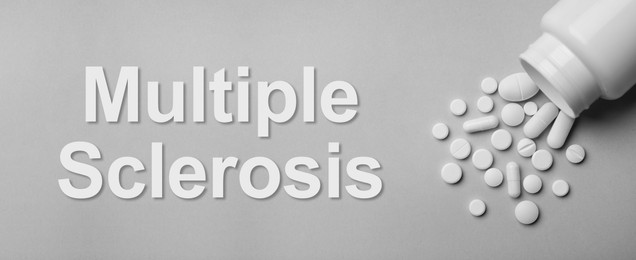 Image of Multiple sclerosis treatment. Bottle with different pills on grey background, flat lay