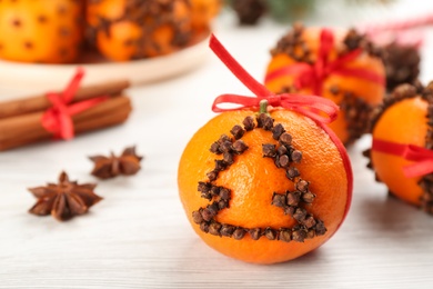 Pomander ball made of fresh tangerine and cloves on white table, space for text