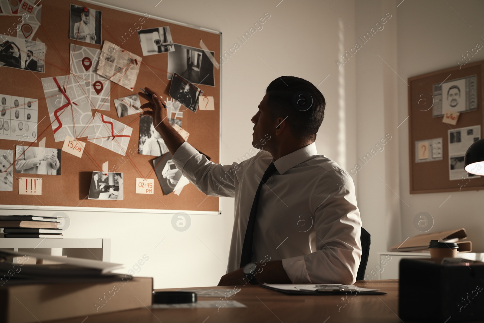 Photo of Detective looking at evidence board in office