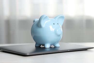 Photo of Piggy bank and laptop on white table indoors