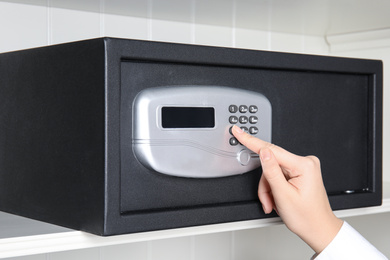 Photo of Woman opening steel safe with electronic lock, closeup