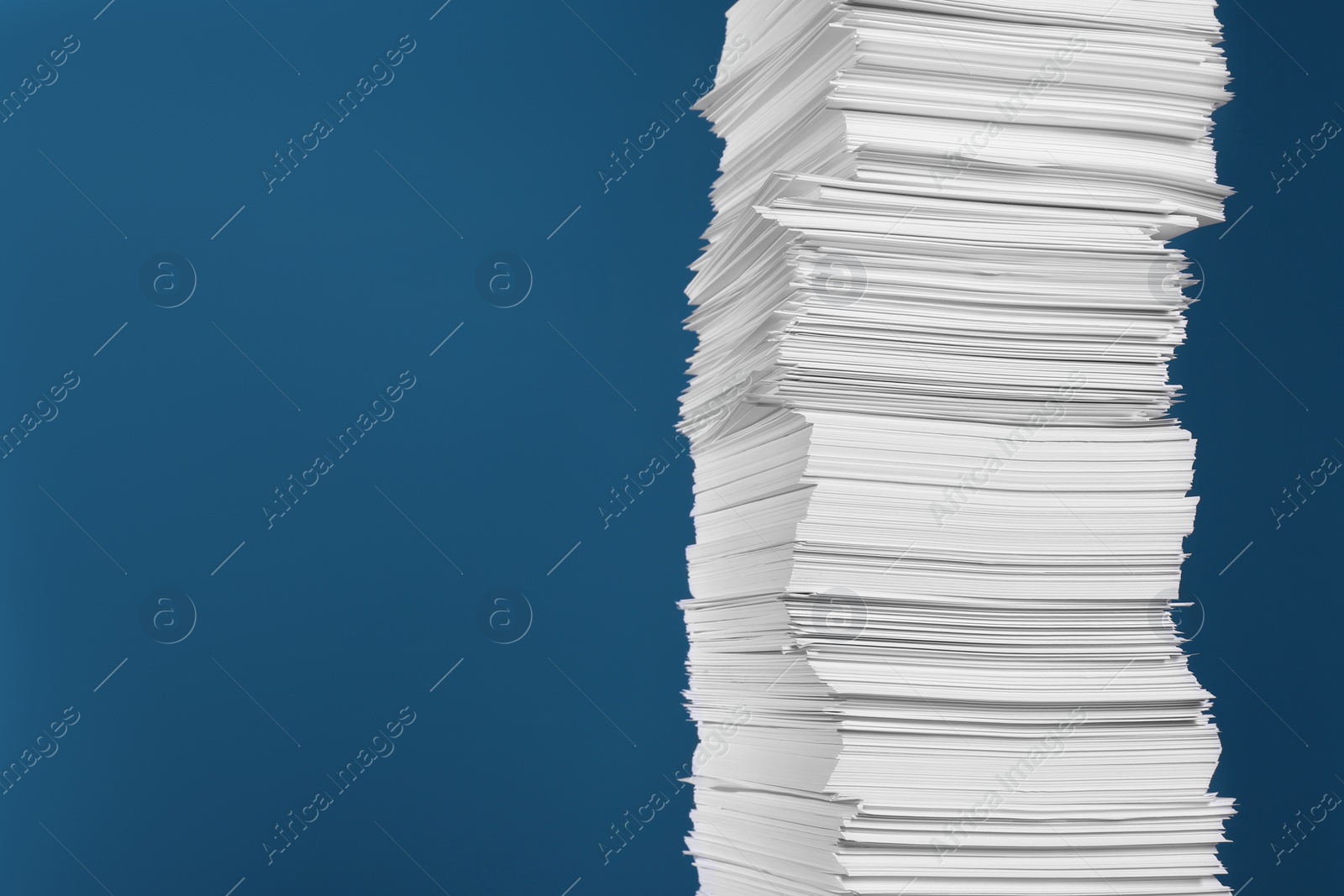 Photo of Stack of white paper sheets on blue background, space for text