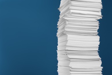 Stack of white paper sheets on blue background, space for text