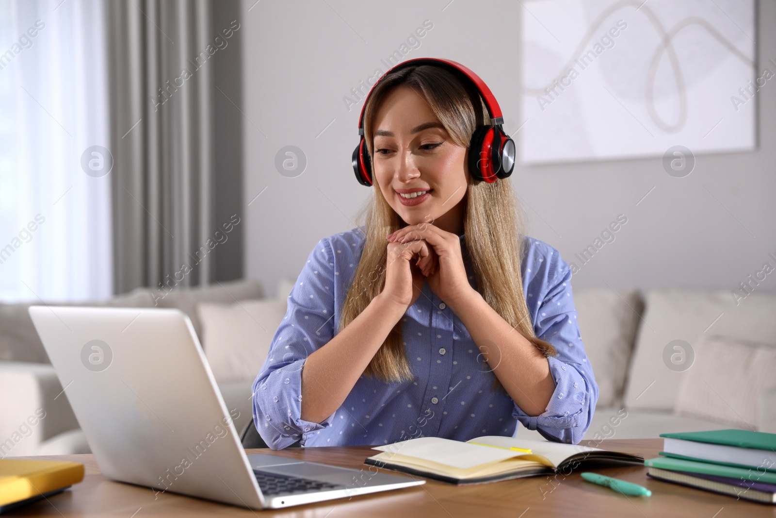 Photo of Young woman watching webinar at table in room