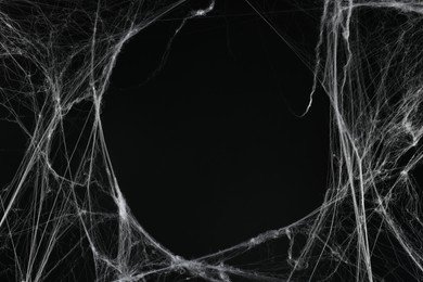 Creepy white cobweb on black background, space for text