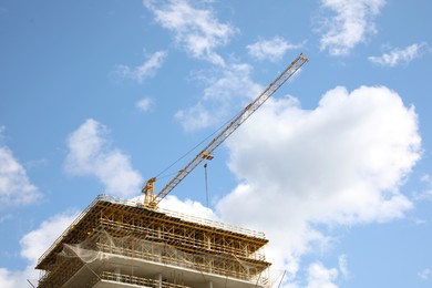 Construction site with tower crane on unfinished building under blue cloudy sky